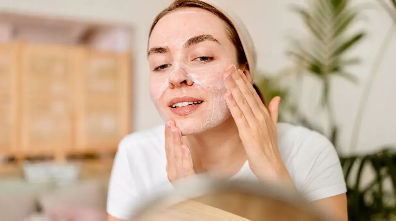 Donna applica detergente viso con schiuma, massaggiando delicatamente per una pelle pulita e luminosa. Ecco come si usa il detergente viso.