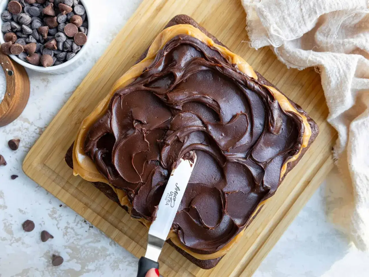 Application d'une ganache au chocolat onctueuse sur un brownie, prête à refroidir au congélateur.