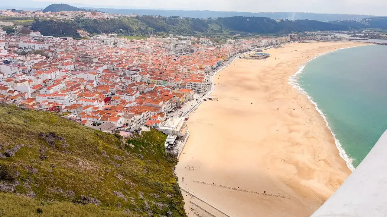 Coastal town with red roofs and a wide sandy beach, perfect for a porto to lisbon bike tour.