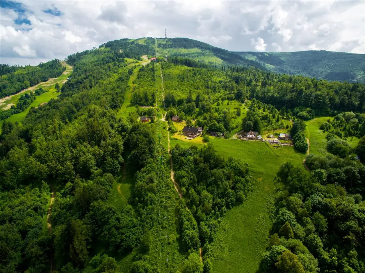 Zielone zbocza Skrzycznego, z widokiem na domki i wyciąg. Wspaniałe widoki na Beskidy.