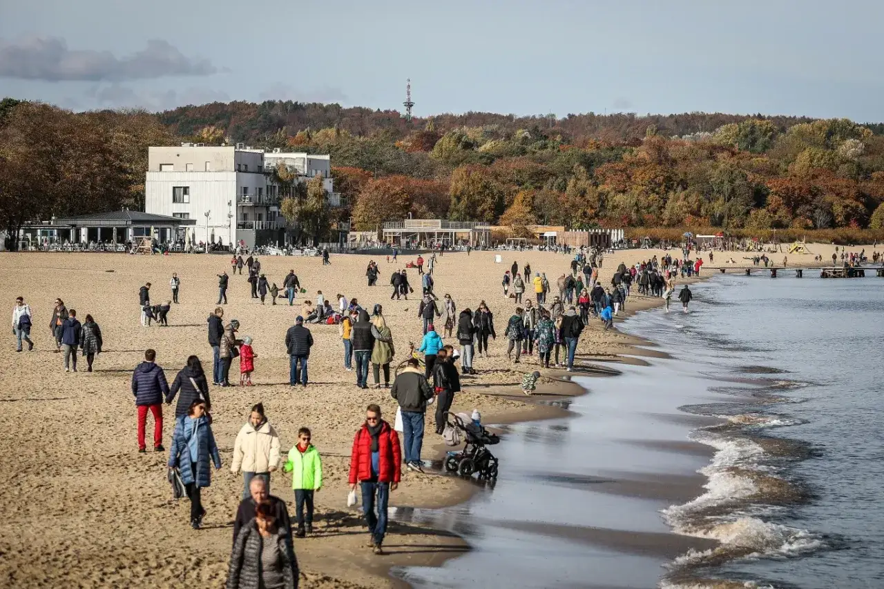 Ludzie spacerują po plaży, ciesząc się jesiennym słońcem. Idealne miejsce, gdzie nad morze we wrześniu.