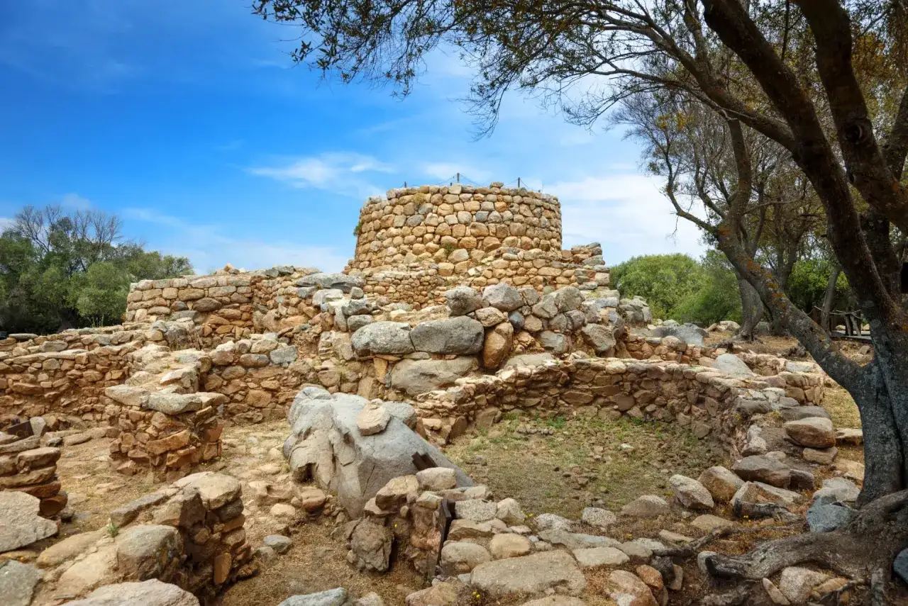 Rovine di un nuraghe sotto un cielo azzurro. Questi antichi monumenti servivano a scopi difensivi e abitativi.