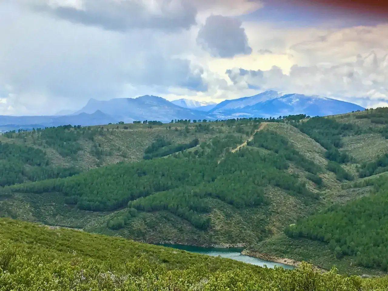 Paisaje monta&ntilde;oso con picos nevados y un embalse, ideal para descubrir qu&eacute; ver en Robledillo de la Jara.
