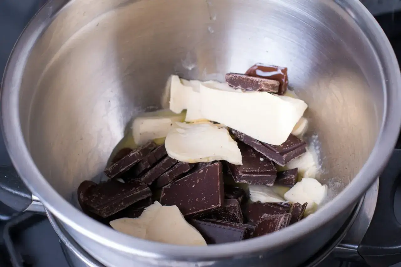 Pour faire un bain-marie, on place du chocolat noir et du beurre dans un bol au-dessus d'une casserole d'eau fr&eacute;missante.
