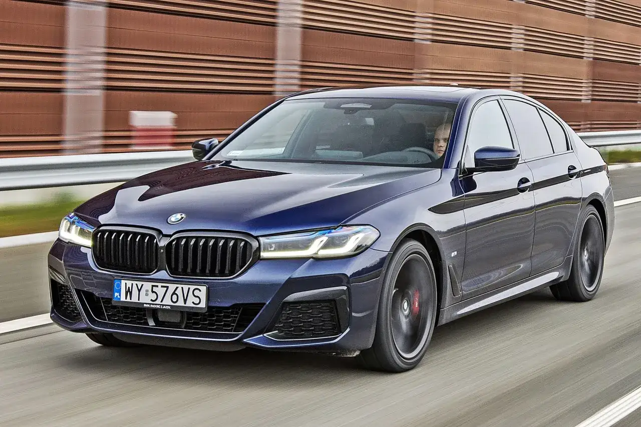 Ciemnoniebieskie BMW 530 mknie po drodze, kierowca skupiony na trasie.