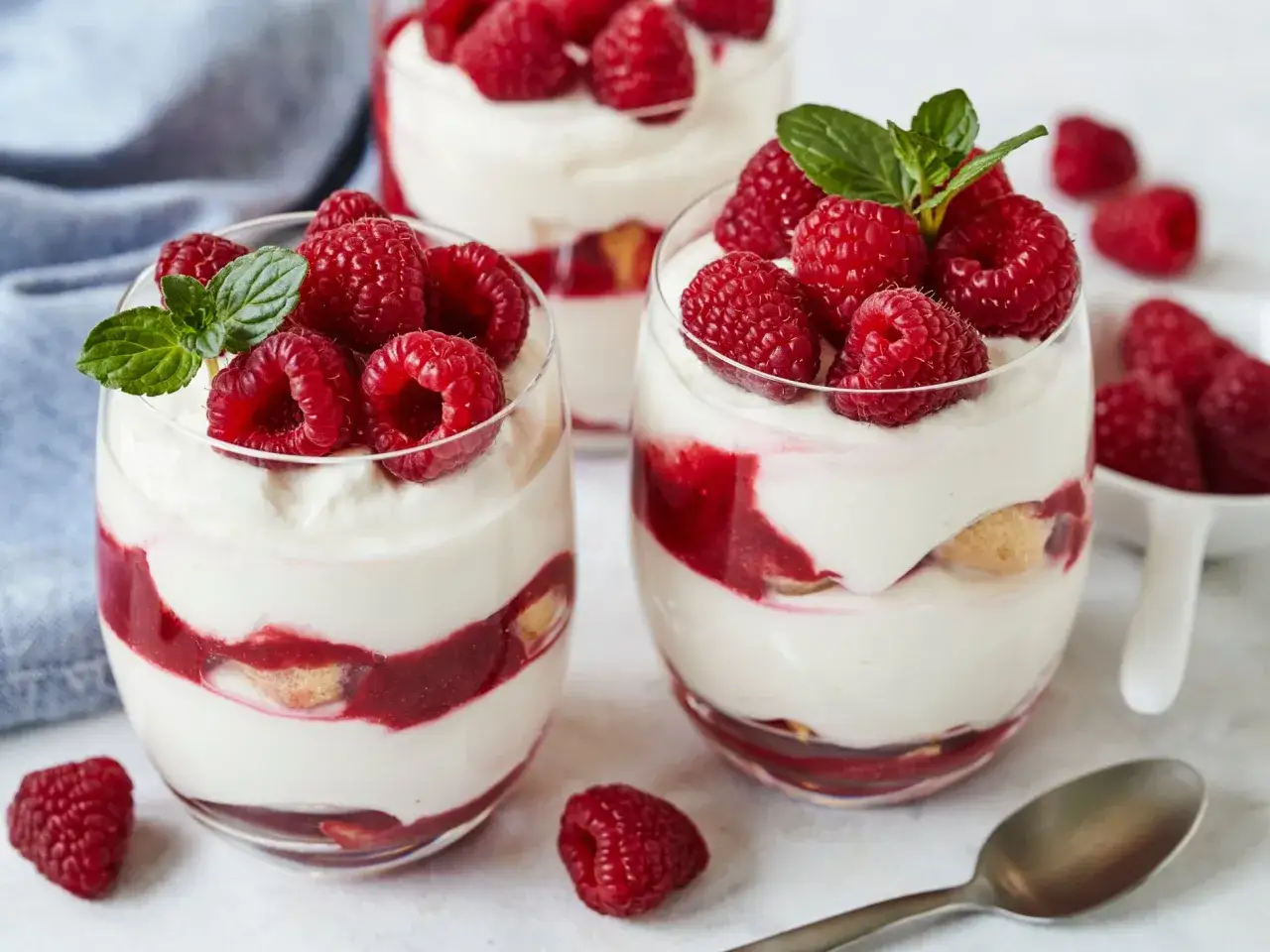 Himbeer Tiramisu mit Joghurt und Mascarpone, geschichtet mit Löffelbiskuits und frischen Himbeeren, garniert mit Minze.