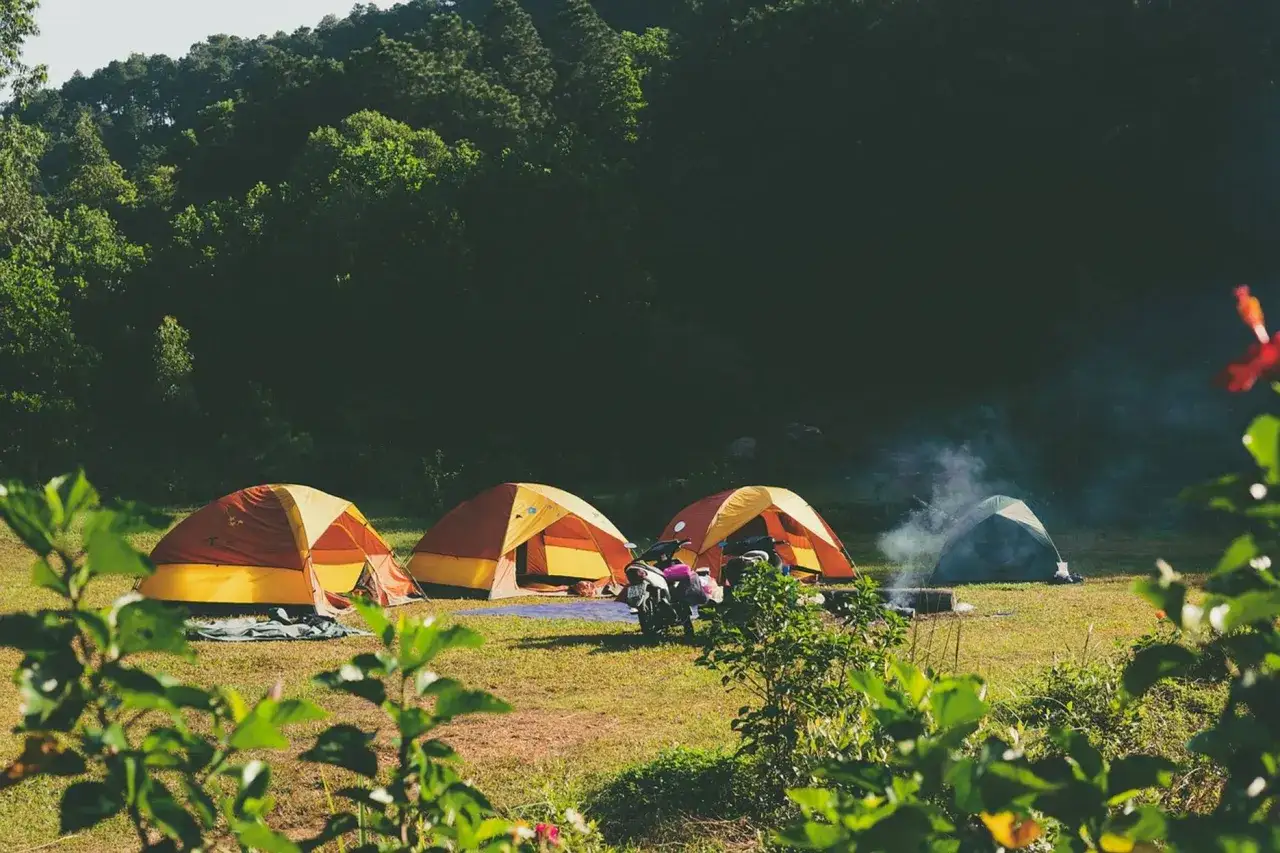 Namiotowe miasteczko na polanie, idealne na **camping Bieszczady**. Motocykl czeka na wyprawę po górskich szlakach.