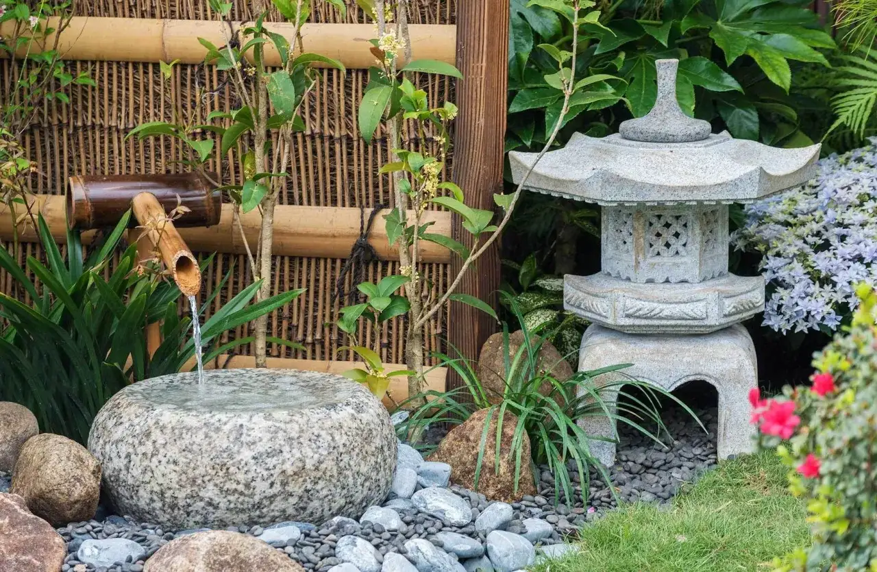 Ein friedlicher asiatischer Garten mit einem Bambusbrunnen, einer Steinlaterne und &uuml;ppiger Vegetation.