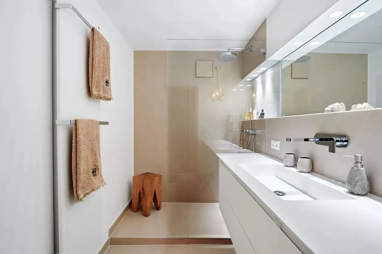 Bagni bellissimi immagini: un bagno moderno con lavabo bianco, specchio illuminato, doccia a pioggia e asciugamani morbidi.