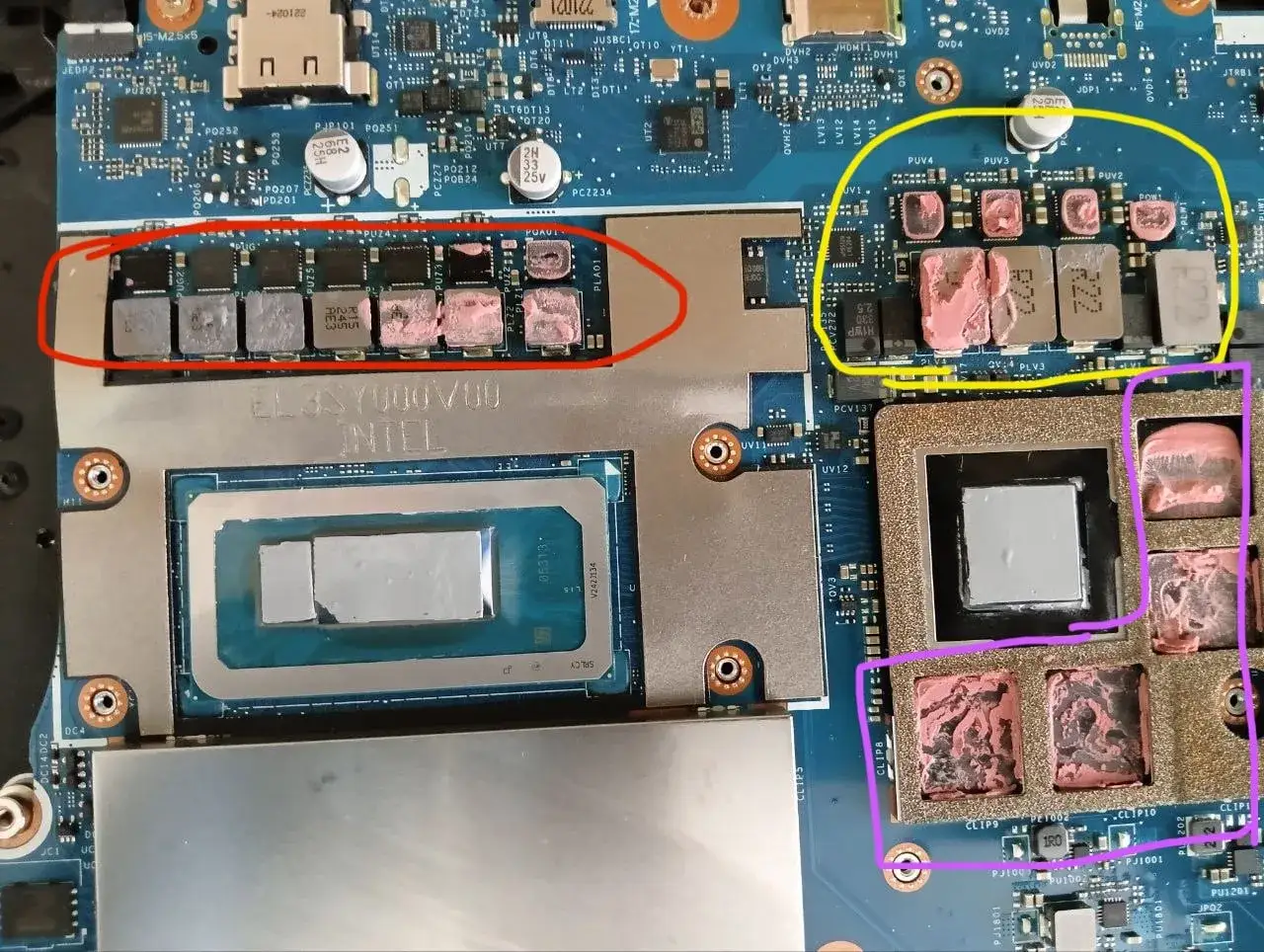 Płyta główna laptopa z widocznymi elementami, w tym procesorem Intel. Wokół niektórych komponentów widać różowe termopady.