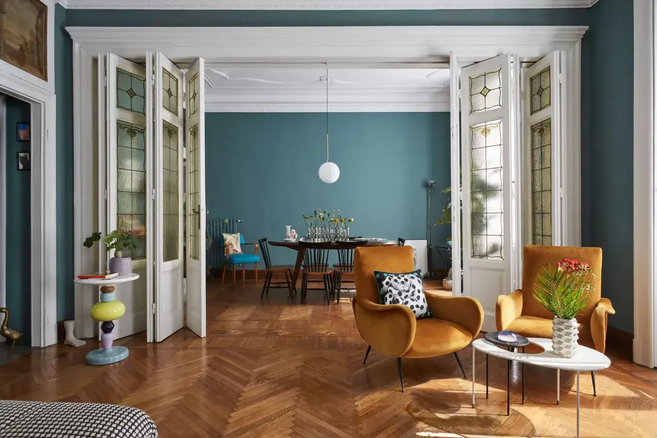 Soggiorno e sala da pranzo con mobili colorati e porte a soffietto in vetro piombato. Idee per appartamenti moderni con un tocco vintage.