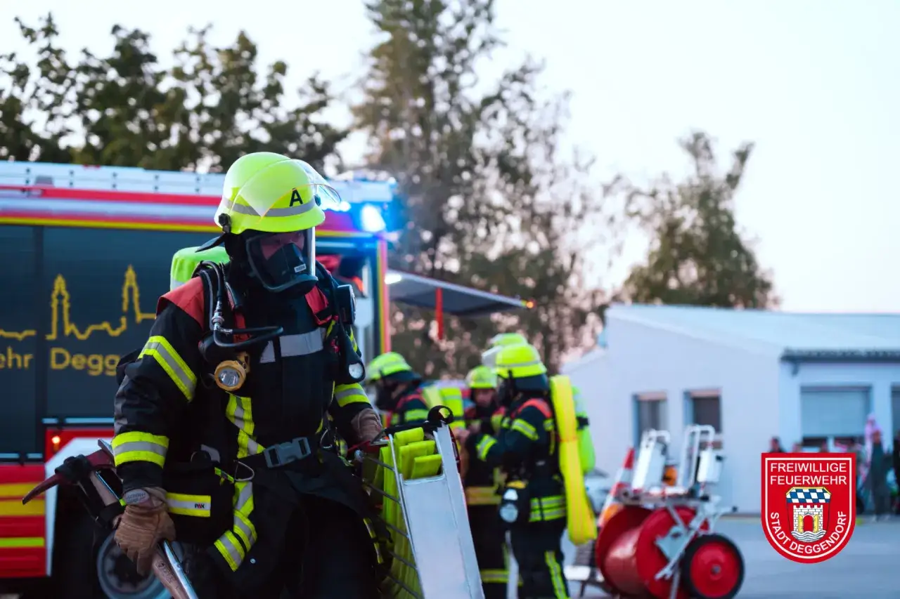 Feuerwehrleute in voller Montur bereiten sich auf den Tag der Feuerwehr vor. Ein Feuerwehrmann trägt eine Leiter.