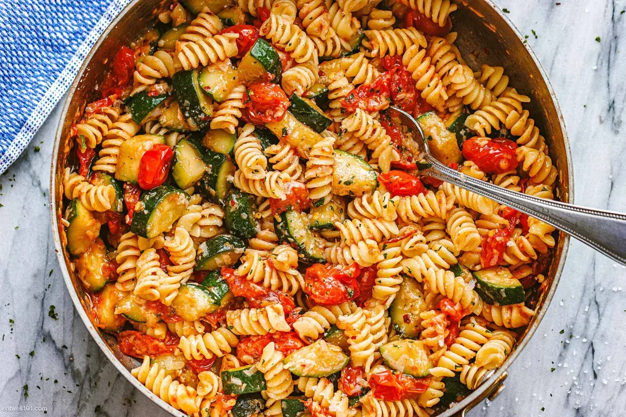 Pyszny obiad z cukinii: makaron fusilli z kawałkami cukinii i pomidorków koktajlowych w sosie.