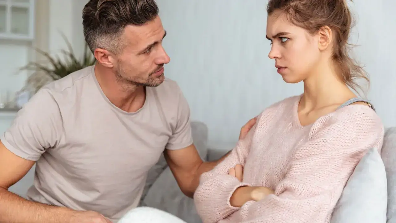 Un uomo cerca di consolare una donna arrabbiata, ma lei è ferita. Quando si tradisce è finito l'amore, e il suo sguardo lo dimostra.