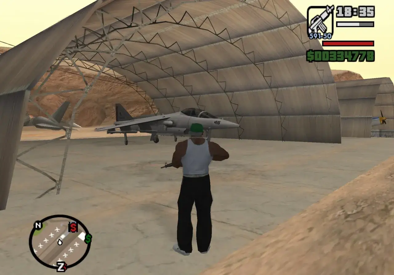 Gracz z bronią w hangarze, obok myśliwca. Może to być scena z gry, gdzie szuka się kodu na hydre gta sa.