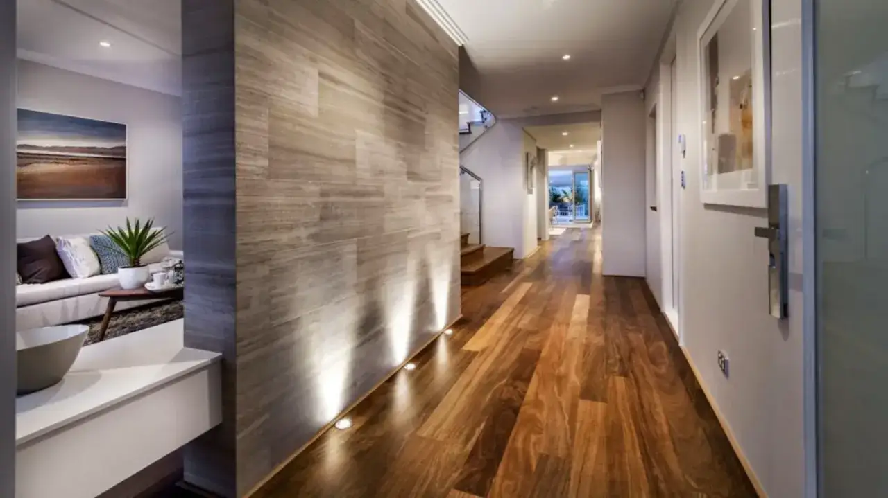 Un corridoio stretto con pavimenti in legno e un muro di pietra. Idee per un corridoio moderno e accogliente.