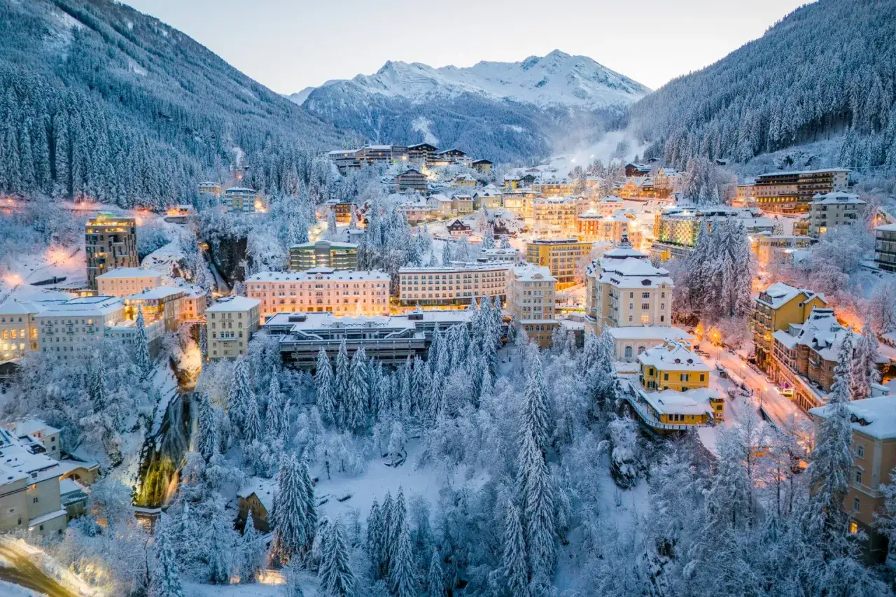 Zimowa noc w dolinie Gastein. Oświetlone budynki i ośnieżone drzewa tworzą magiczny krajobraz.