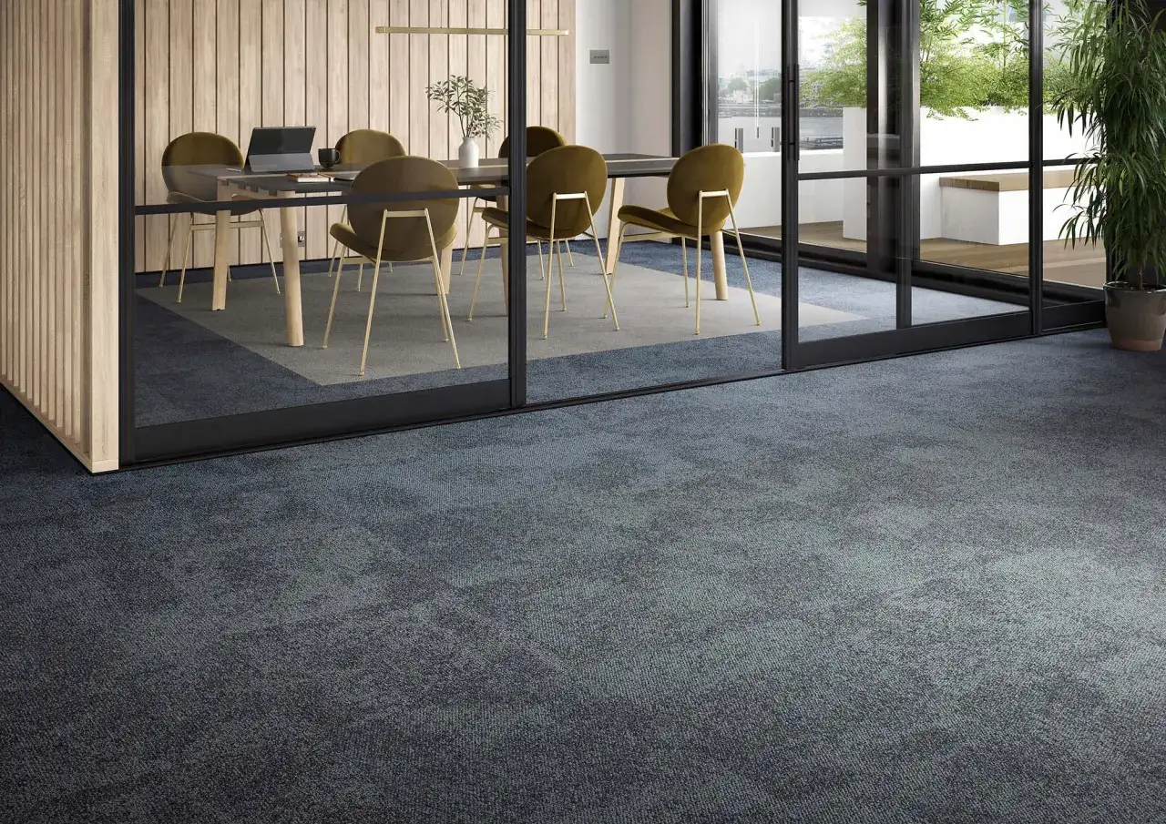 Una moqueta moderna de color azul oscuro cubre el suelo de una sala de reuniones con paredes de madera y sillas doradas.
