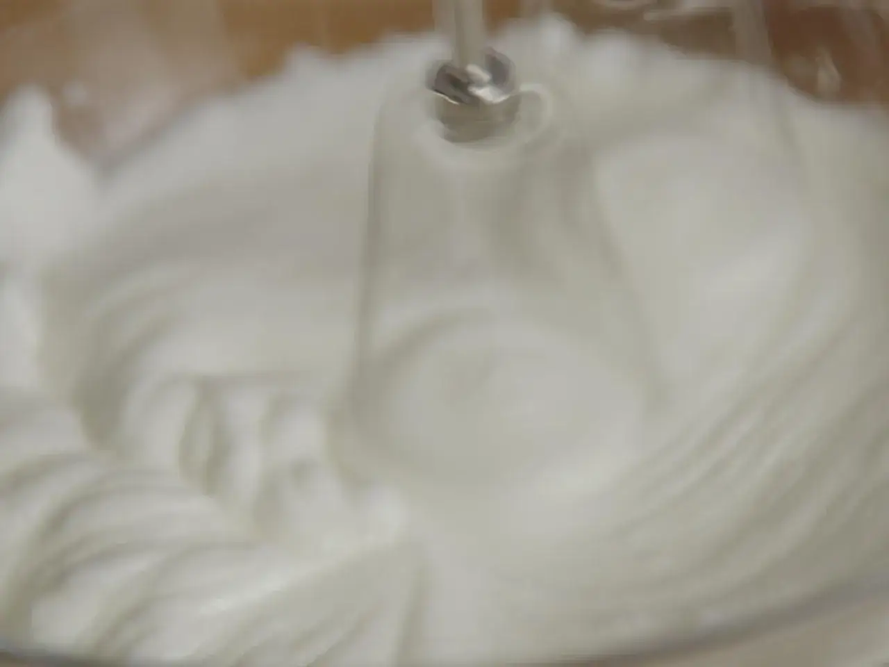 Mousse aérienne en cours de préparation, le batteur électrique transforme l'oeuf blanc en une texture légère et vaporeuse.