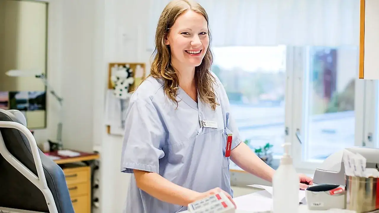 Sjuksköterska ler glatt vid sitt skrivbord, redo att utföra ett diagnos test.