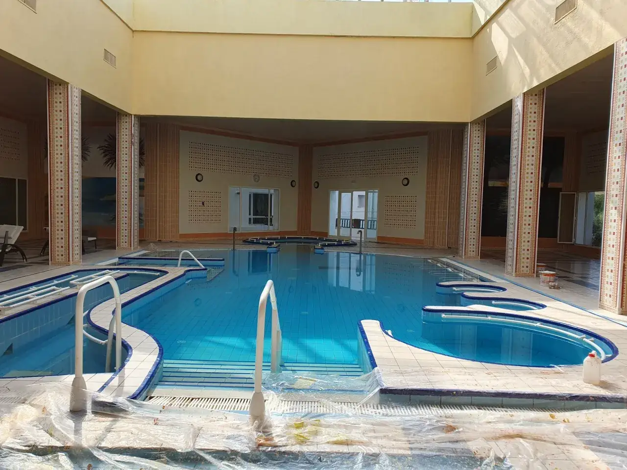 Wnętrze basenu w Mahdia Palace, z błękitną wodą i schodkami.