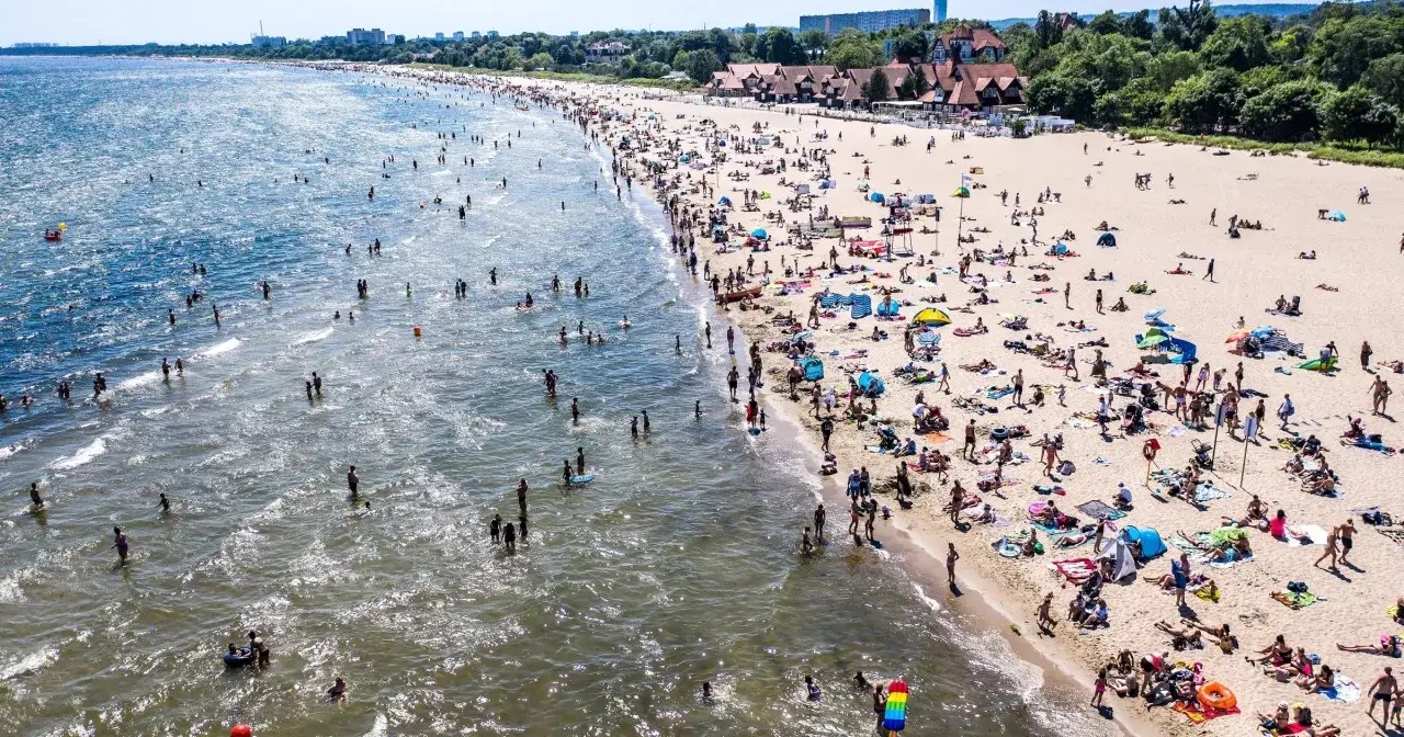 Tłum ludzi na plaży i w wodzie. W sierpniu Bałtyk jest przyjemnie ciepły, idealny do kąpieli.