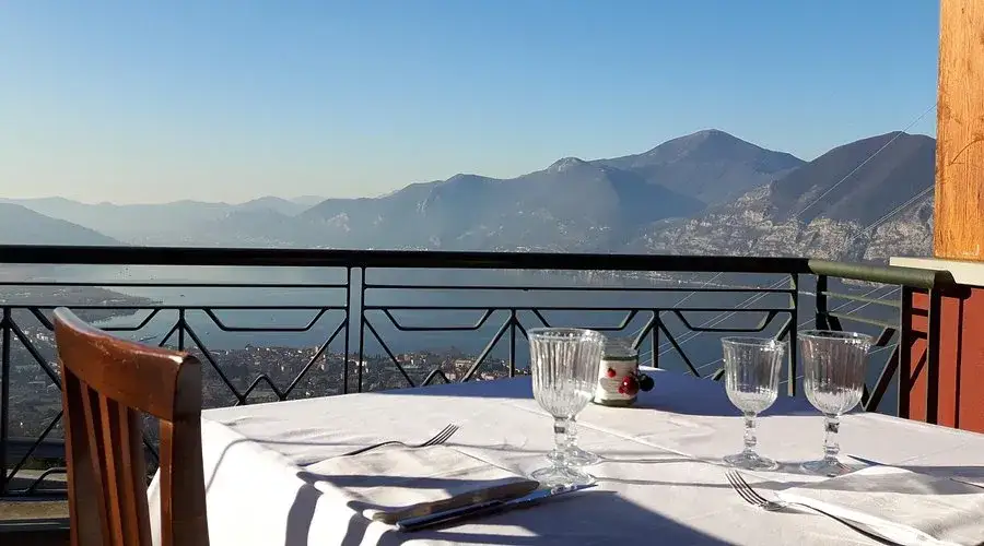 Tavola apparecchiata con vista mozzafiato su lago e montagne, un'esperienza unica tra i ristoranti particolari Brescia e provincia.