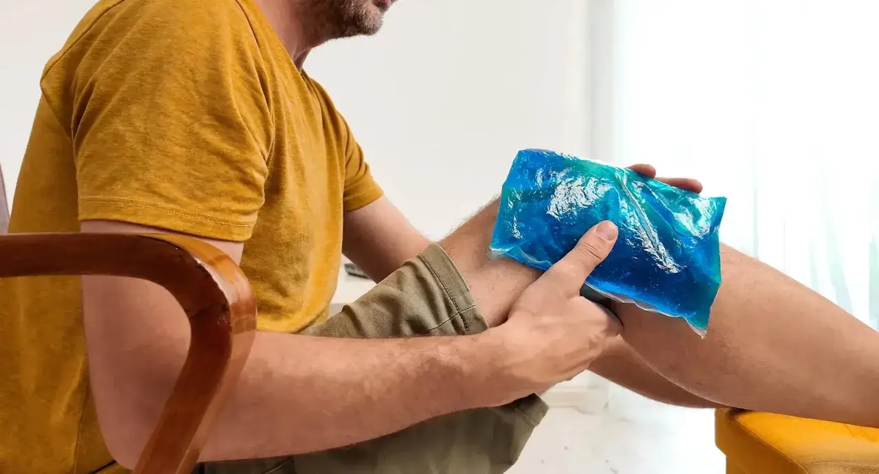 Mann k&uuml;hlt ein dickes Knie mit einem K&uuml;hlpack. Was tun bei Schmerzen? Eis hilft.