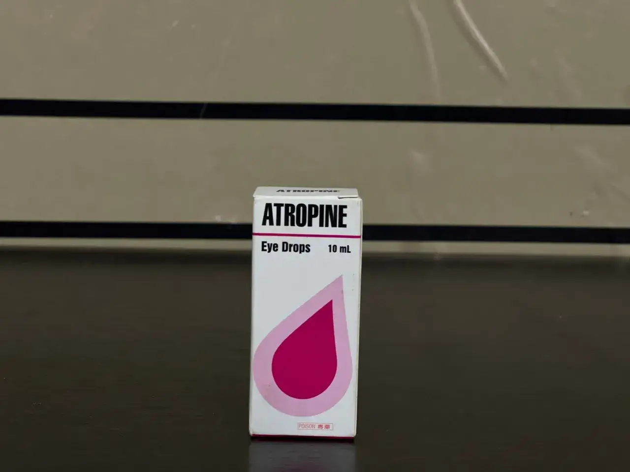 Pudełko kropli do oczu z napisem ATROPINE. Zawiera 10 ml. Zaznaczono, że jest to trucizna.