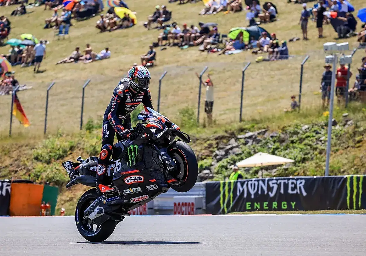 Piloto de MotoGP hoy hace un caballito espectacular con su Aprilia. El p&uacute;blico en las gradas disfruta del espect&aacute;culo.