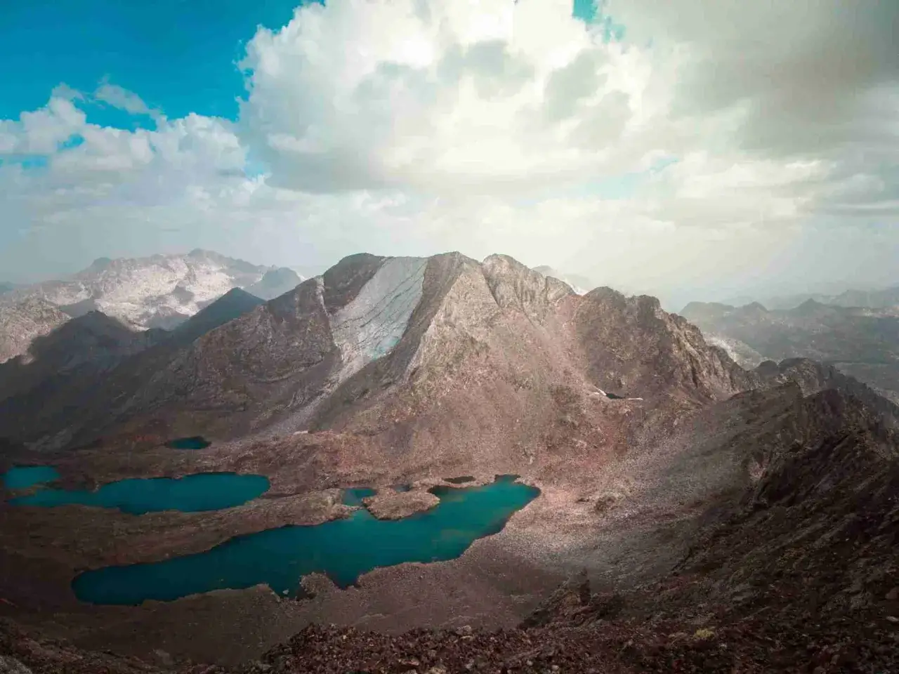 Paisaje montañoso con lagos turquesa, como si fueran los **picos del infierno** en un día nublado.