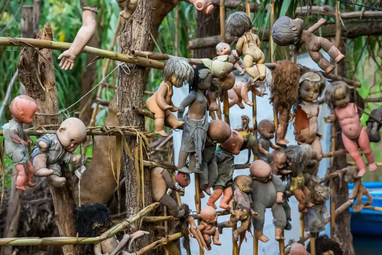 En la Isla de las Muñecas, muñecas viejas y rotas cuelgan de árboles y estructuras, creando una escena espeluznante y melancólica.