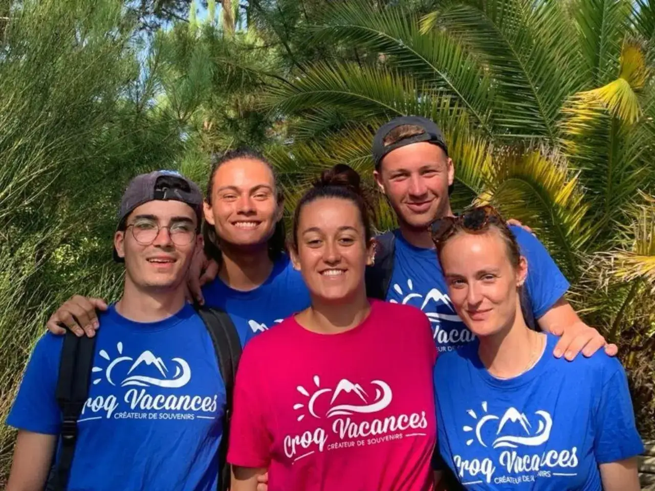 Cinq jeunes souriants, portant des t-shirts