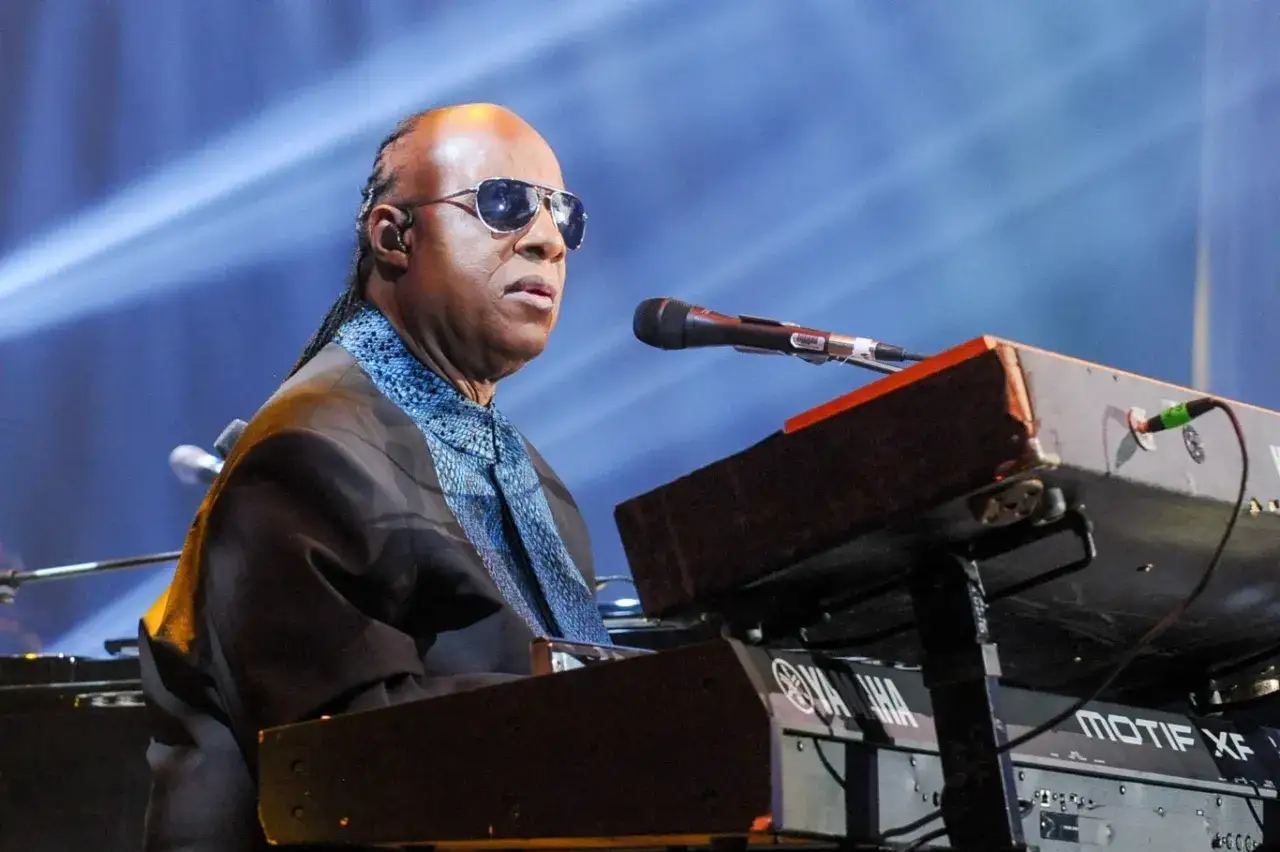 Niewidomy piosenkarz Stevie Wonder gra na keyboardzie Yamaha podczas koncertu.