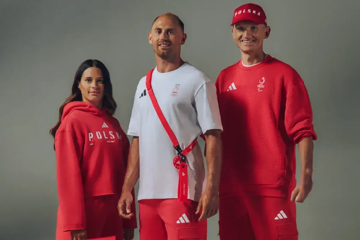 Trzy osoby w czerwono-białych strojach sportowych z napisem 