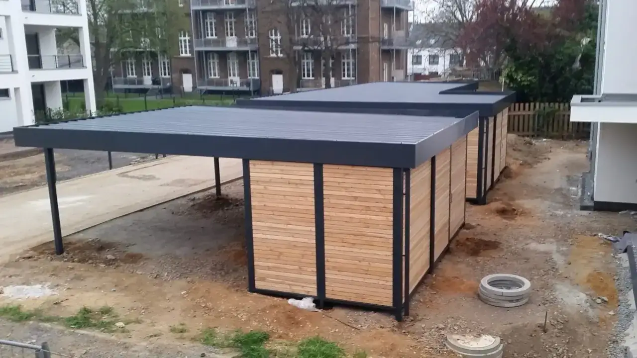 Moderne Carports mit Holzwänden und einem begehbaren Dach, die auf einer Baustelle stehen.