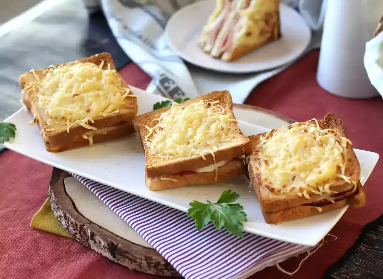 Trois croque monsieur dor&eacute;s et gratin&eacute;s, pr&eacute;par&eacute;s &agrave; l'airfryer, sur une assiette blanche avec du persil.