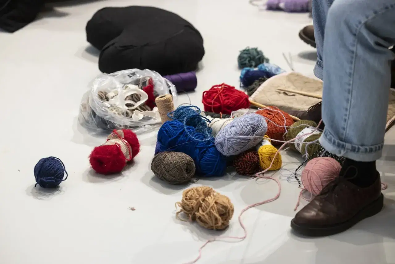 Elin Berlin sitter omgiven av garn i olika färger och texturer, redo för ett kreativt projekt.