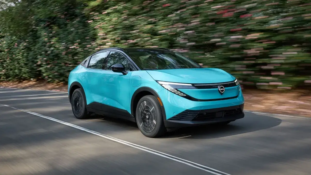 En turkos Nissan Ariya glider fram p&aring; en v&auml;g, omgiven av gr&ouml;nska. Kanske &auml;r det en ny modell som l&ouml;ser gamla Nissan Leaf problem.