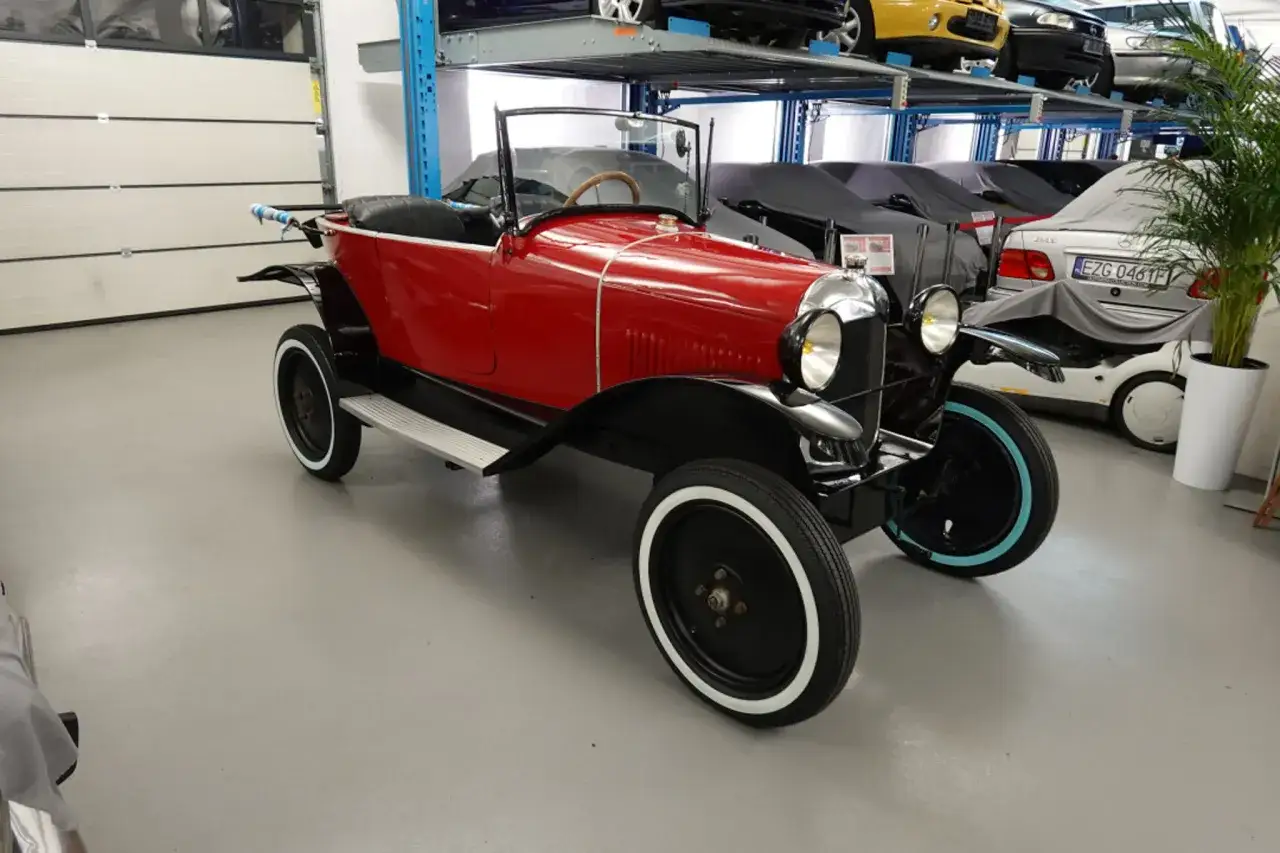 Czerwony, zabytkowy Citroen, jeden z wielu **citroen modele stare**, błyszczy w garażu obok innych klasyków.