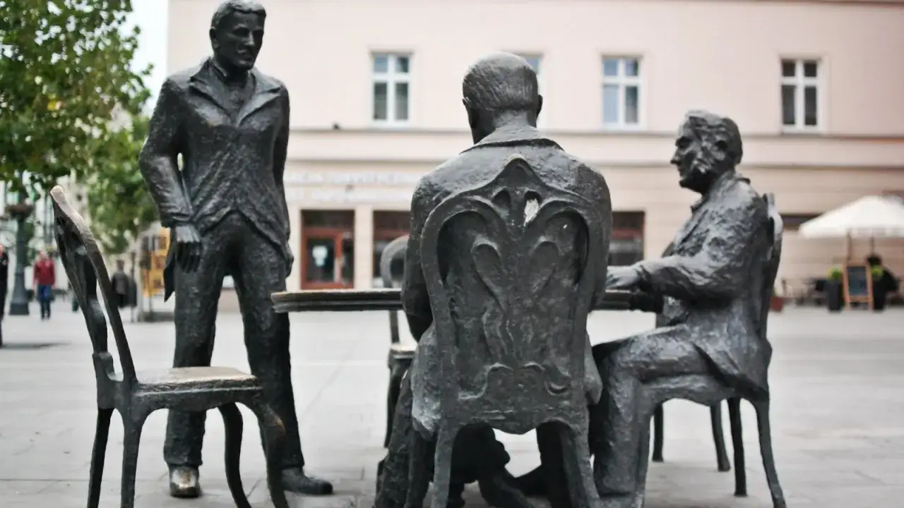 Rzeźby na Piotrkowskiej w Łodzi: trzej panowie przy stole, jeden stoi.