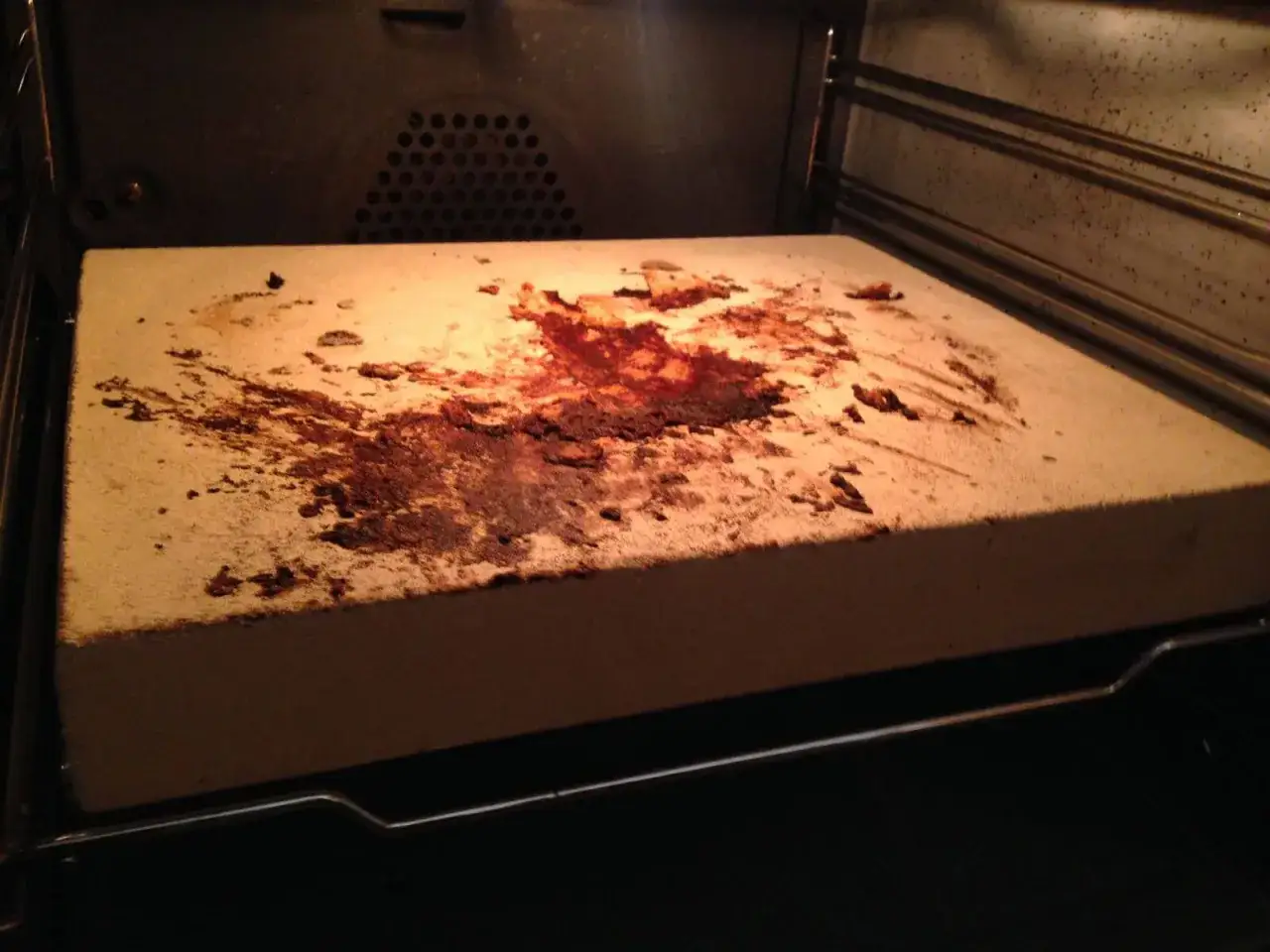 Ein verschmutzter pizzastein mit eingebrannten Essensresten. Sieht aus, als h&auml;tte sich darauf etwas Schimmel gebildet.