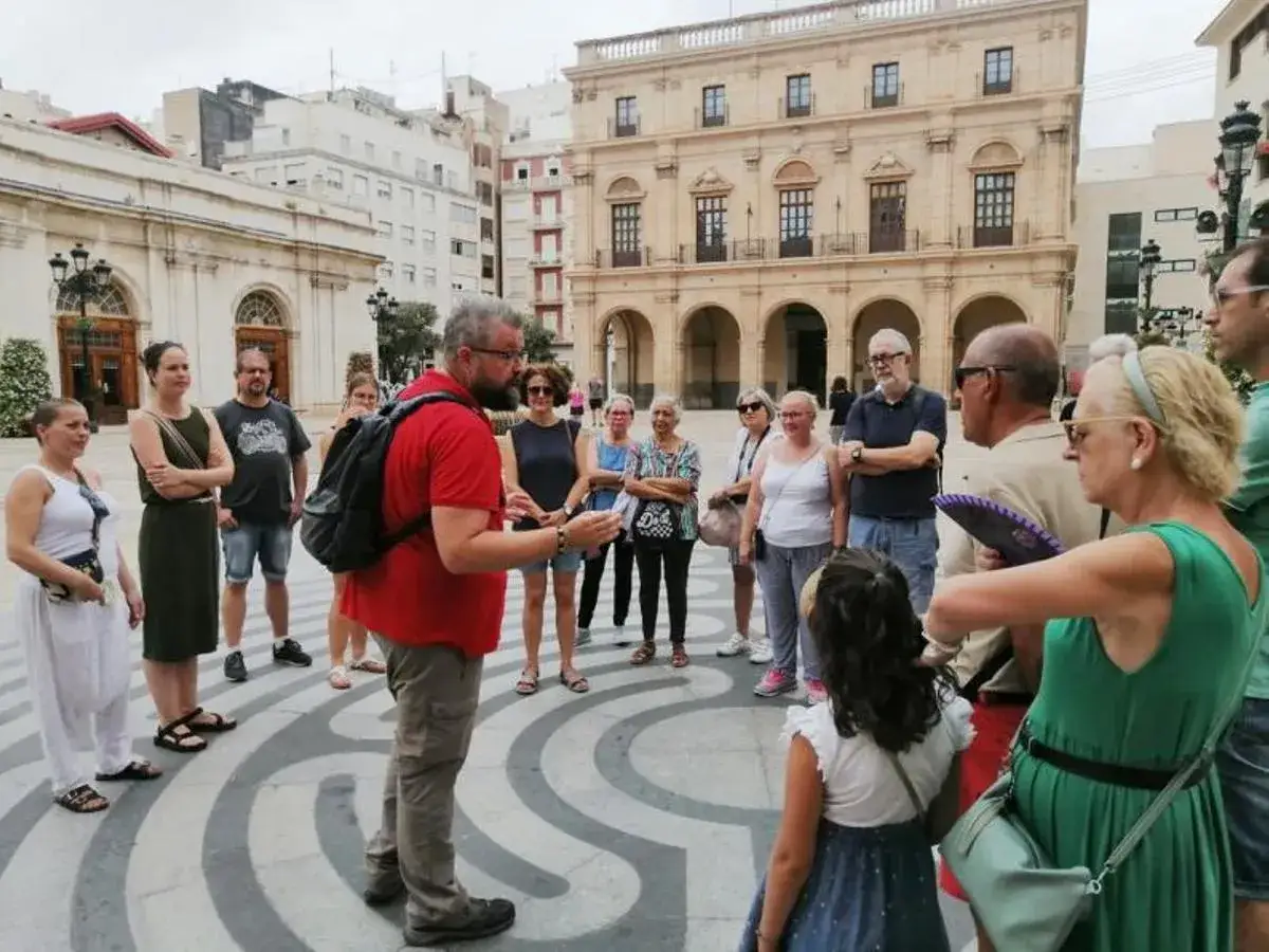 Un guía explica la historia de la plaza, quizás cerca del puente de todos los santos, a un grupo de turistas.