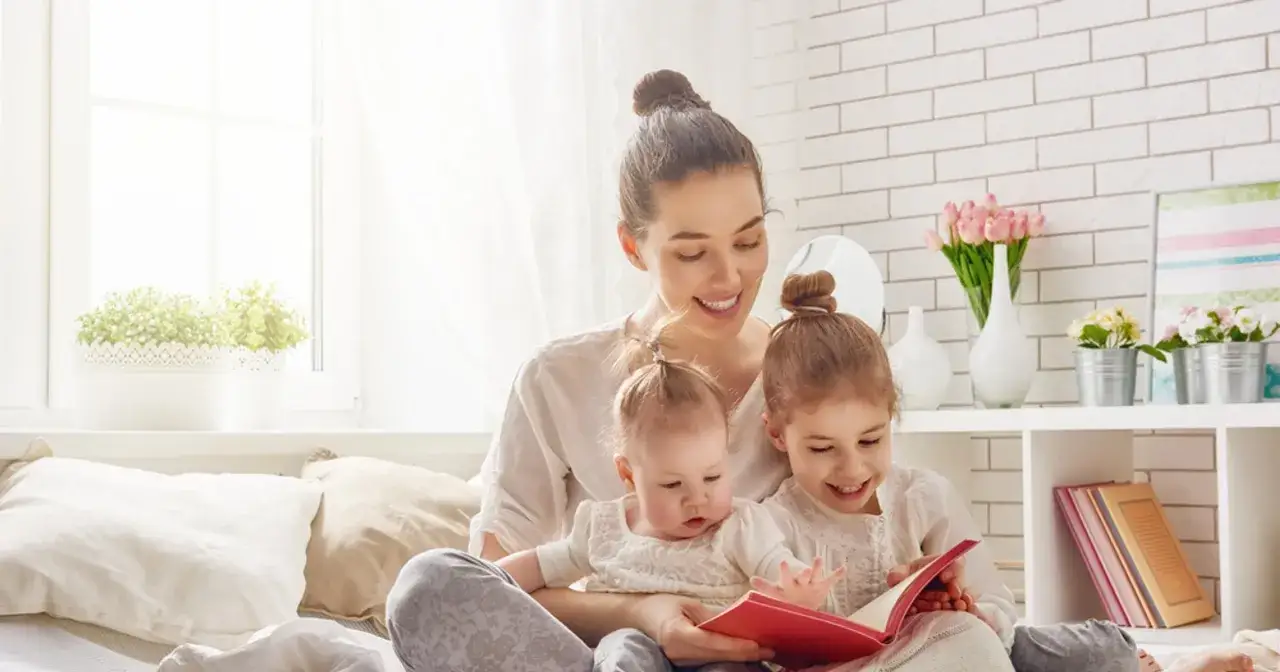 Mama z dwójką dzieci czyta książkę. Może to być inspiracja do ubiegania się o 1000 zł na drugie dziecko.