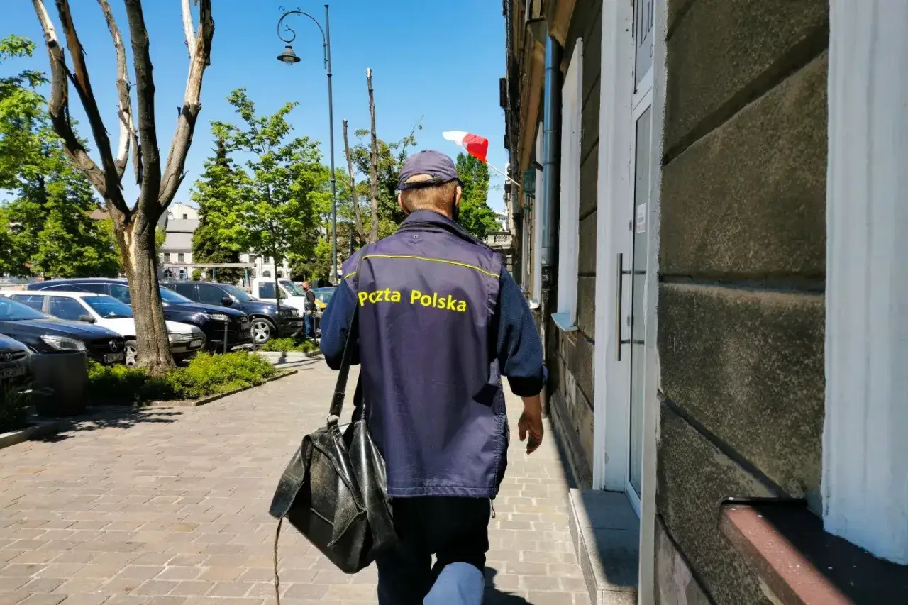Listonosz w granatowej kurtce z napisem 