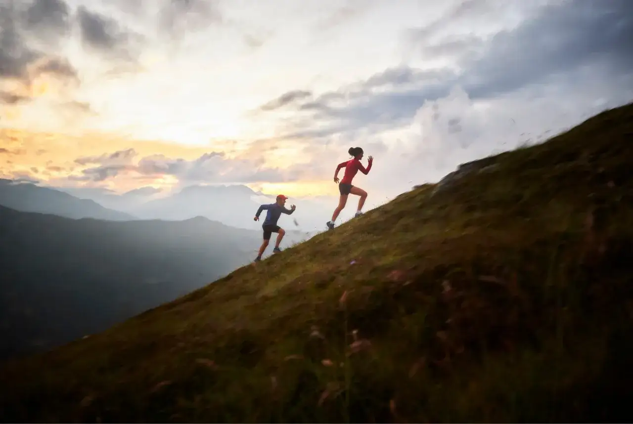 Deux coureurs s'entraînent en montagne, une belle leçon pour savoir comment progresser en course à pied. Le soleil se lève sur les sommets.