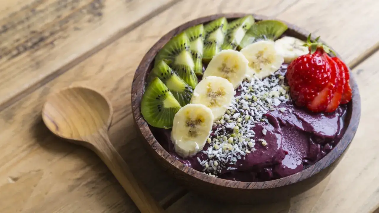 Miska pełna smoothie z owoc&oacute;w acai, ozdobiona plasterkami banana, kiwi i truskawką. Idealne śniadanie, by dowiedzieć się, acai co to jest.