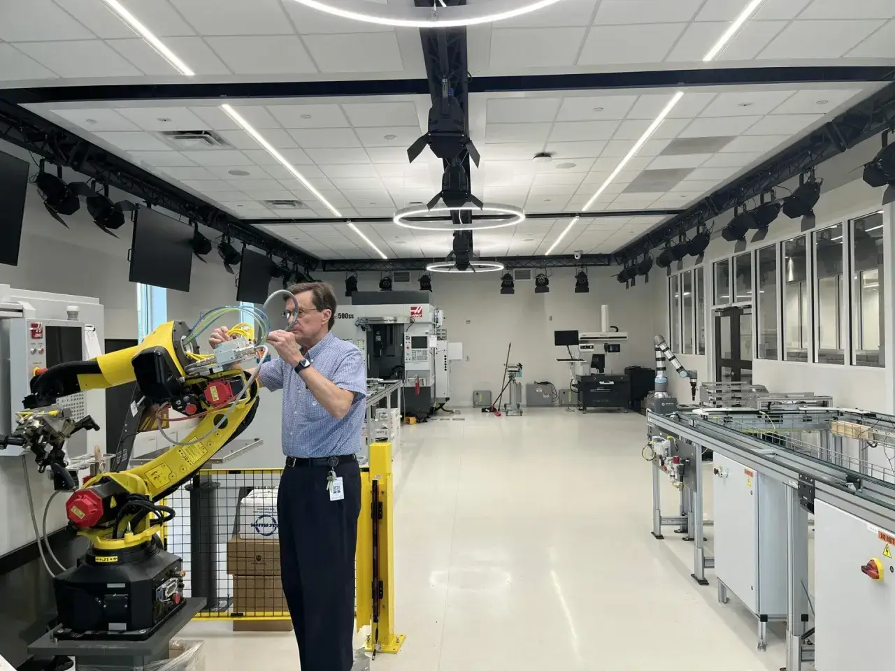 Mann arbeitet an einem Roboterarm in einem modernen Labor, das f&uuml;r das Robotik Studium ausgestattet ist.