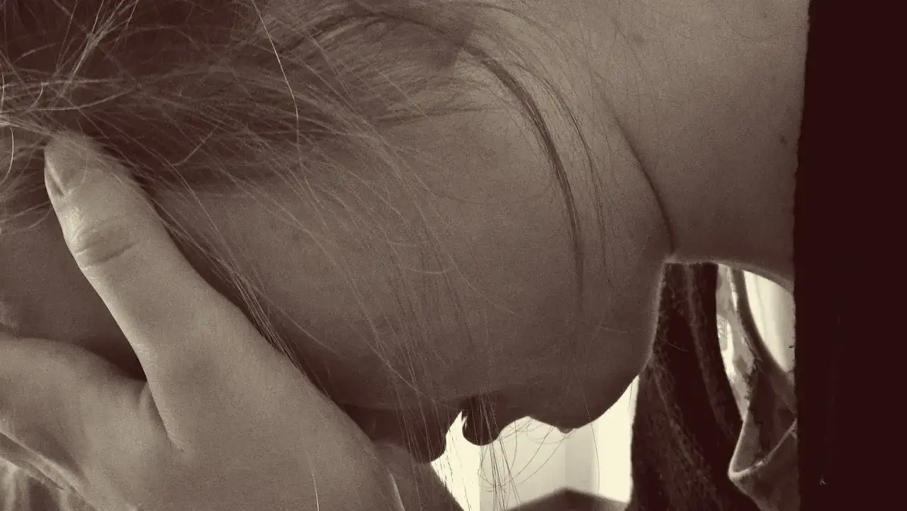 En kvinna med handen mot ansiktet, en bild som kan spegla känslor av gravid depression och utmaningar i familjelivet.