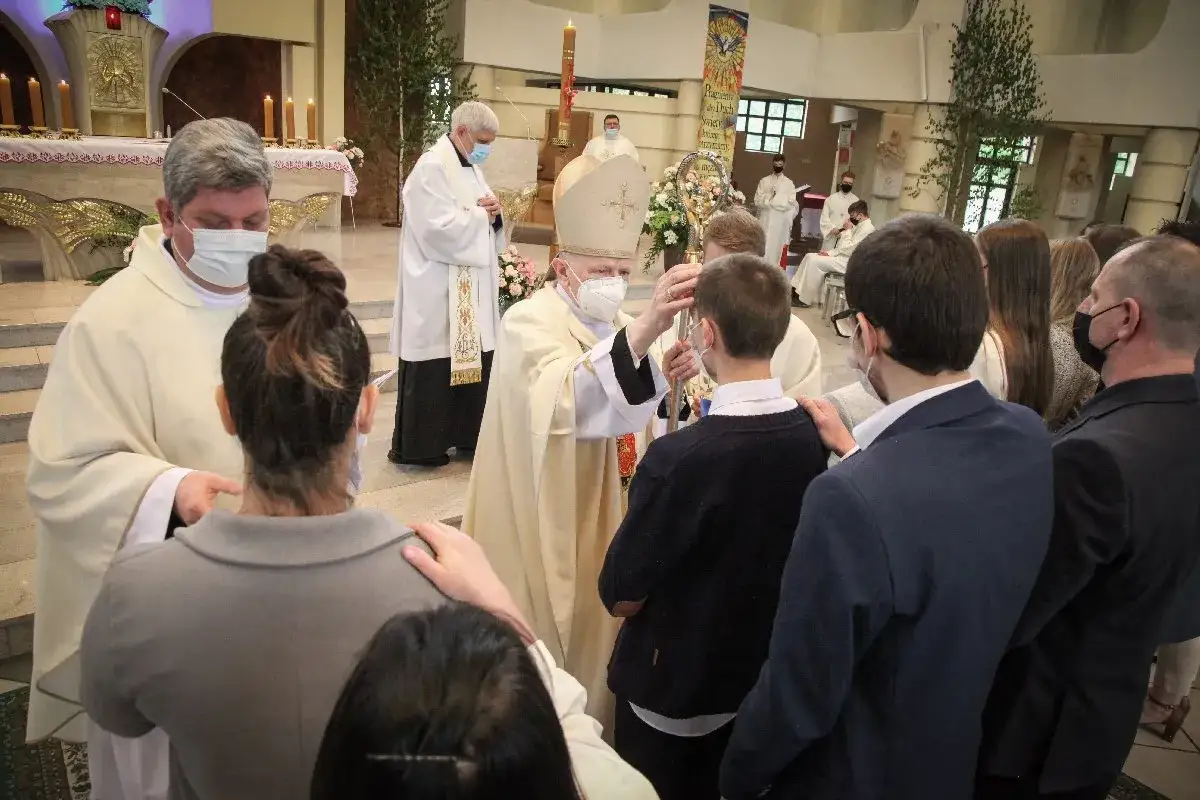 Biskup udziela sakramentu bierzmowania. Ceremonia trwa ok. godziny, a wierni uczestniczą w ważnym wydarzeniu.